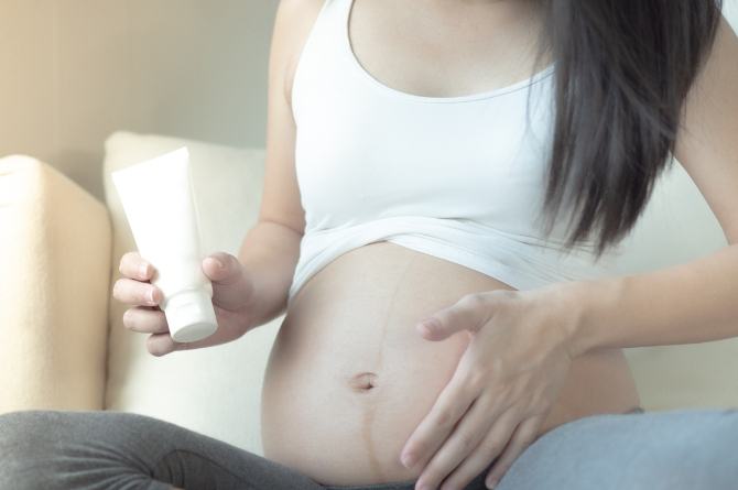 Photo of pregnant woman holding a tube of cream