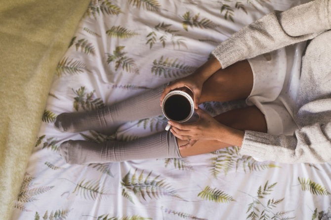 Birds eye view photo of a coffee cup and a person wearing socks